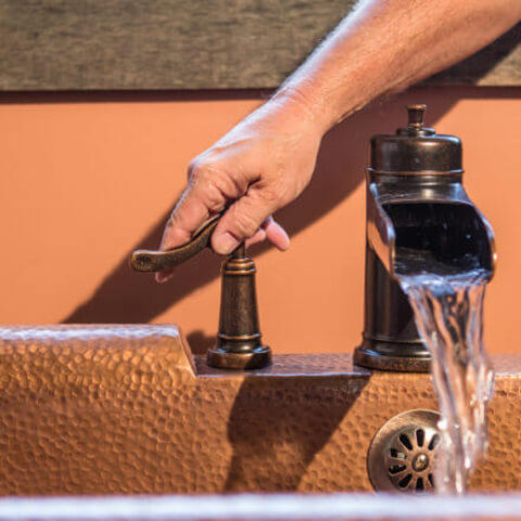 a hand turning on a bathtub faucet