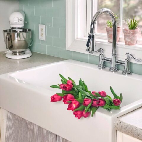a white drop-in apron front fireclay sink with pink flowers in the basin