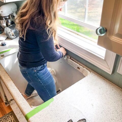 Woman with tools, standing in kitchen construction preparing to install a new kitchen sink