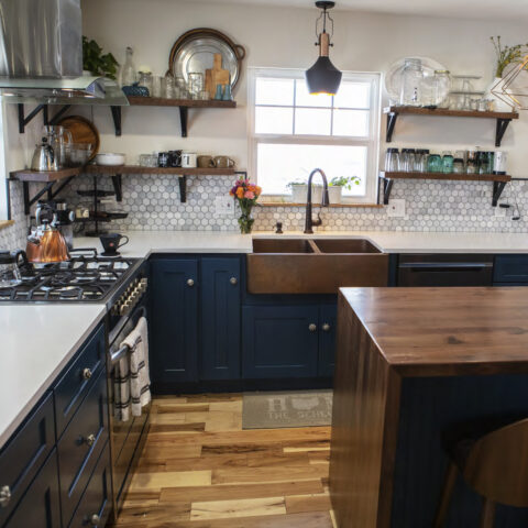 Kitchen with wood table, copper farmhouse sink and blue cabinets.