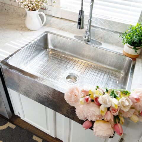 a single bowl crafted stainless steel sink with pink flowers in basin