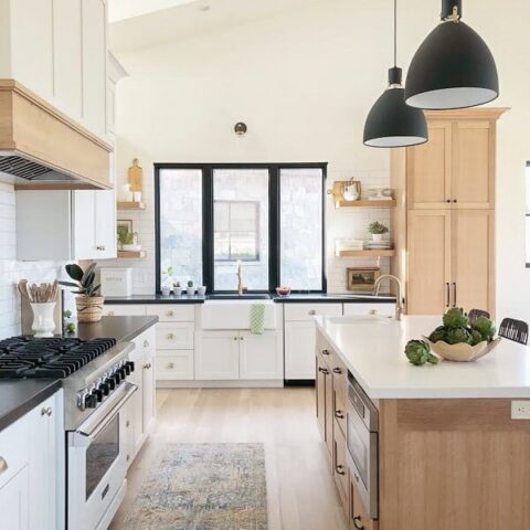 a modern white farmhouse kitchen with a fireclay sink and hanging light fixtures