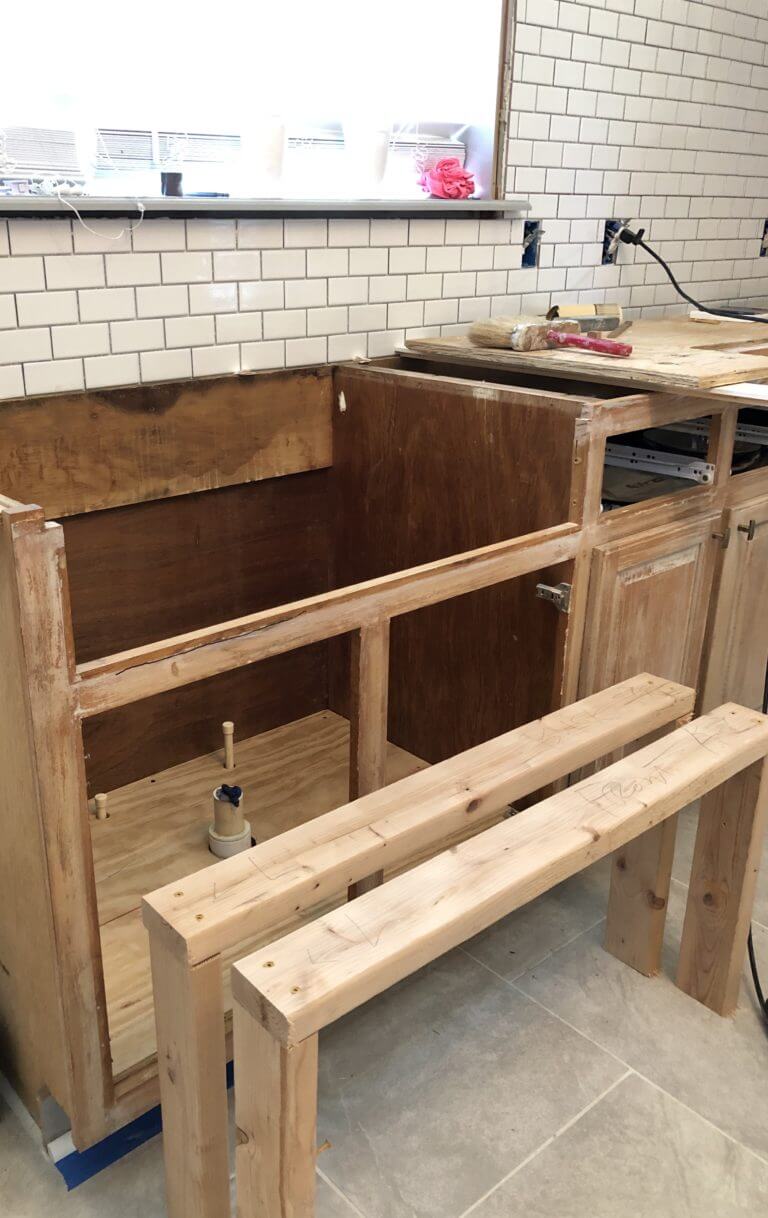 A kitchen under renovation with exposed wooden framing for cabinets, a partially installed countertop, and a subway tile backsplash.