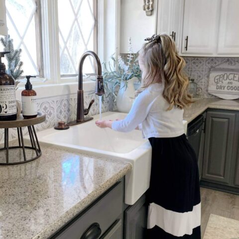 a white fireclay sink with a little girl washing her hands standing on a stool