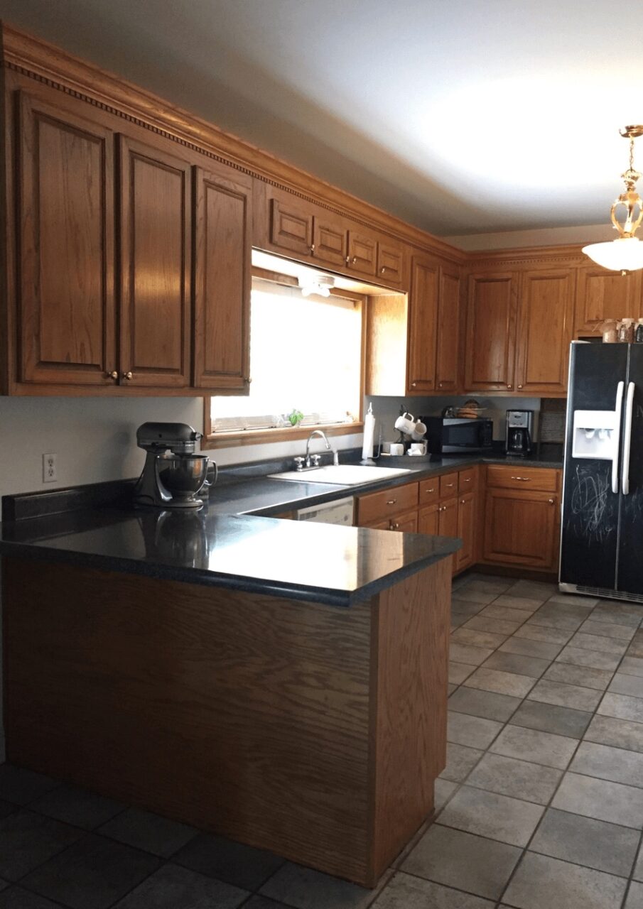 a before image of a kitchen with standard wood cabinets and old white drop-in sink.