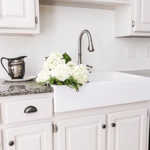 a white fireclay kitchen sink with flowers in the basin