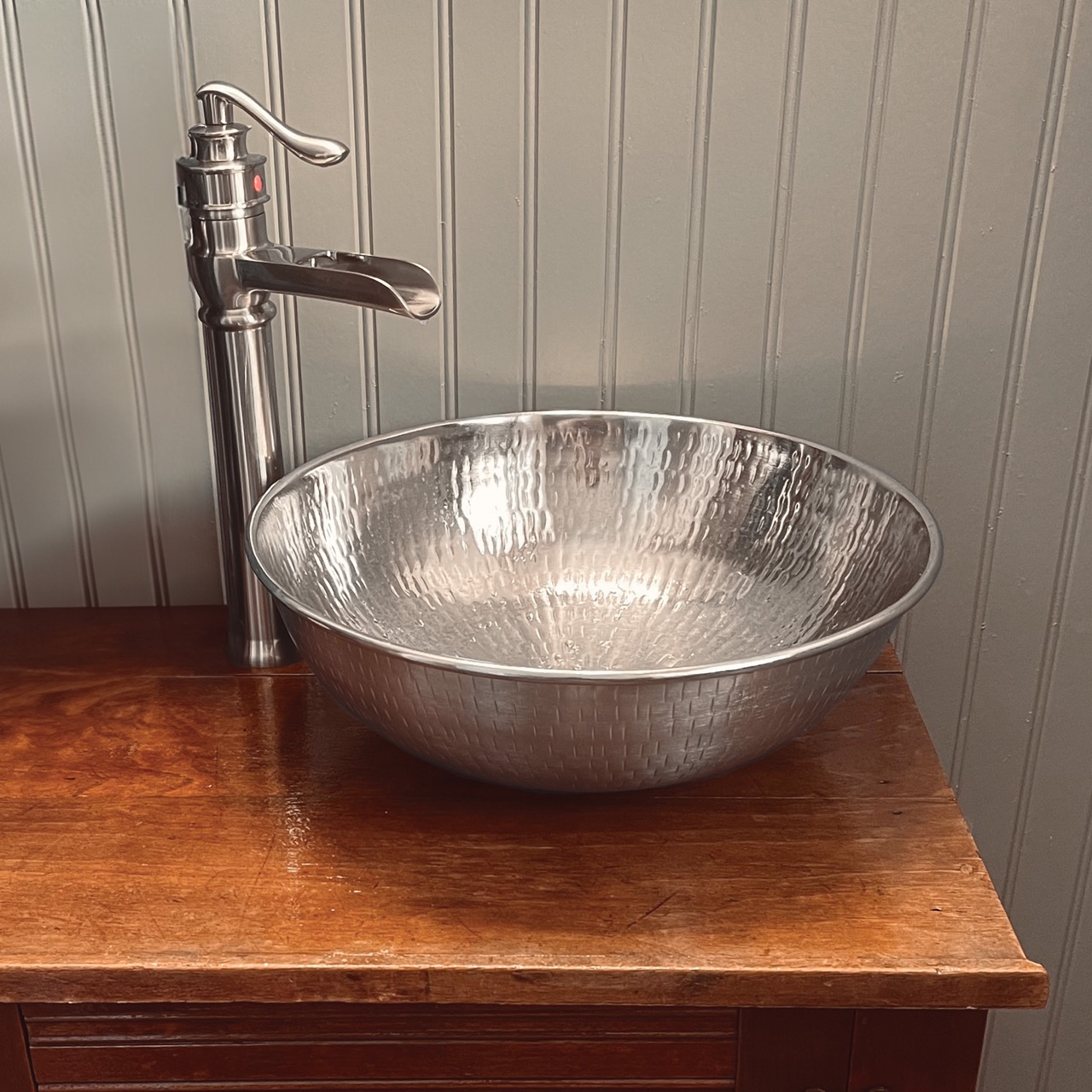A hand hammered nickel vessel bathroom sink.