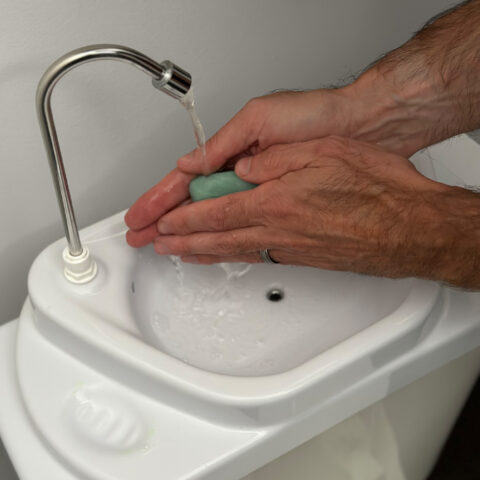 GreenFlow Toilet Sink being used with man washing hands with bar of soap