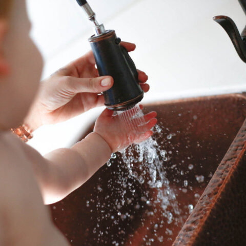 a mother and baby spraying a pull down faucet