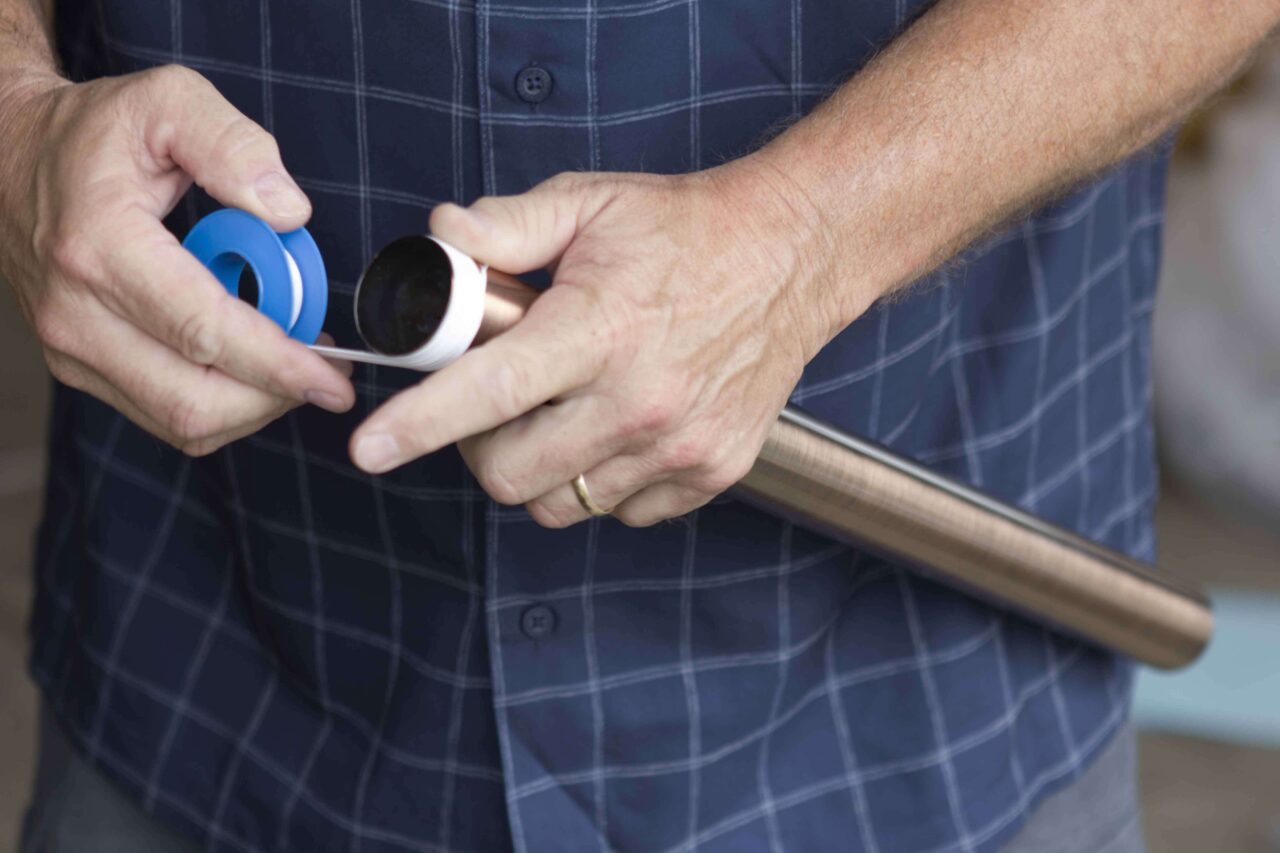 A person applying plumber's tape to a pipe fitting.