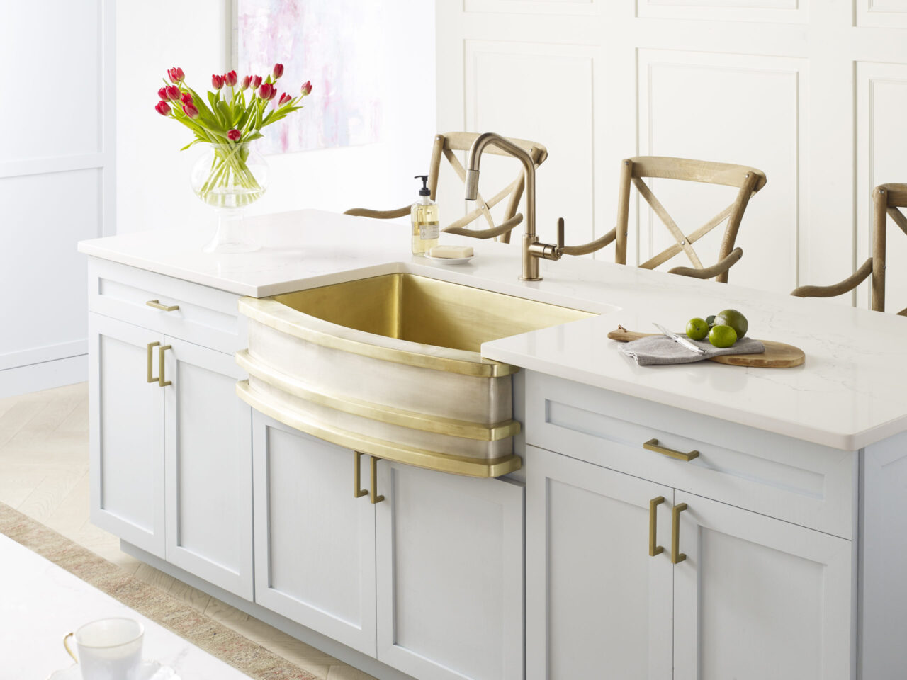 Handcrafted Farmhouse Kitchen Sink in Satin Brass and Burnished Nickel. A trio of satin brass bands run horizontally as a design element across the nickel sink basin which is installed in a traditional kitchen island with 3 chairs at the opposite side for dining.