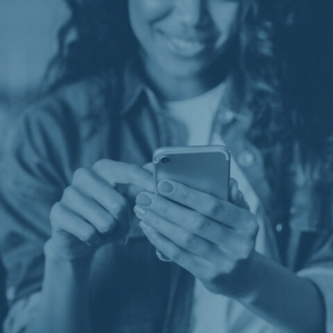 Colorized image of woman holding and looking at her cell phone while smiling