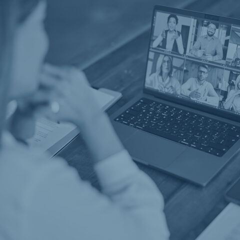 Colorized image of woman sitting facing laptop computer on a virtual call with other participants at her desk